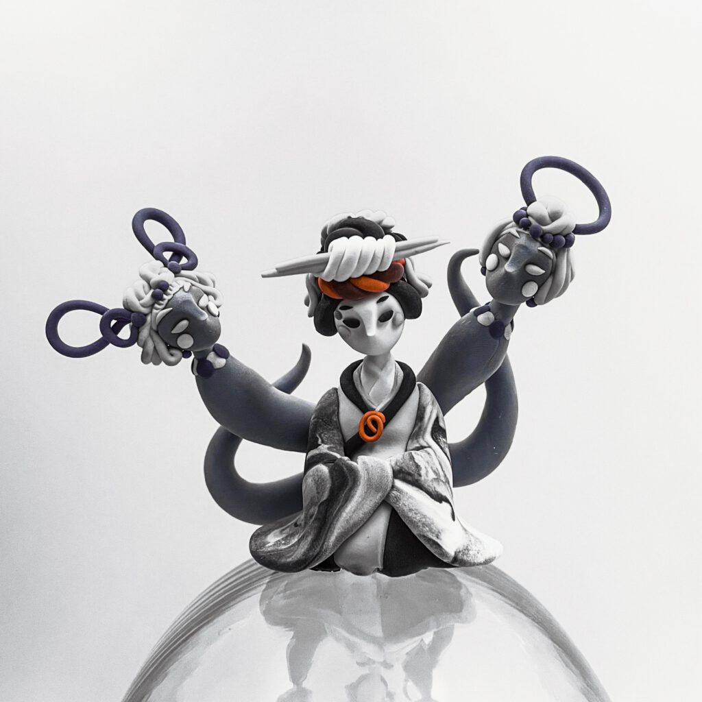 Black and white photograph of a sitting geisha with serpentine figures emerging