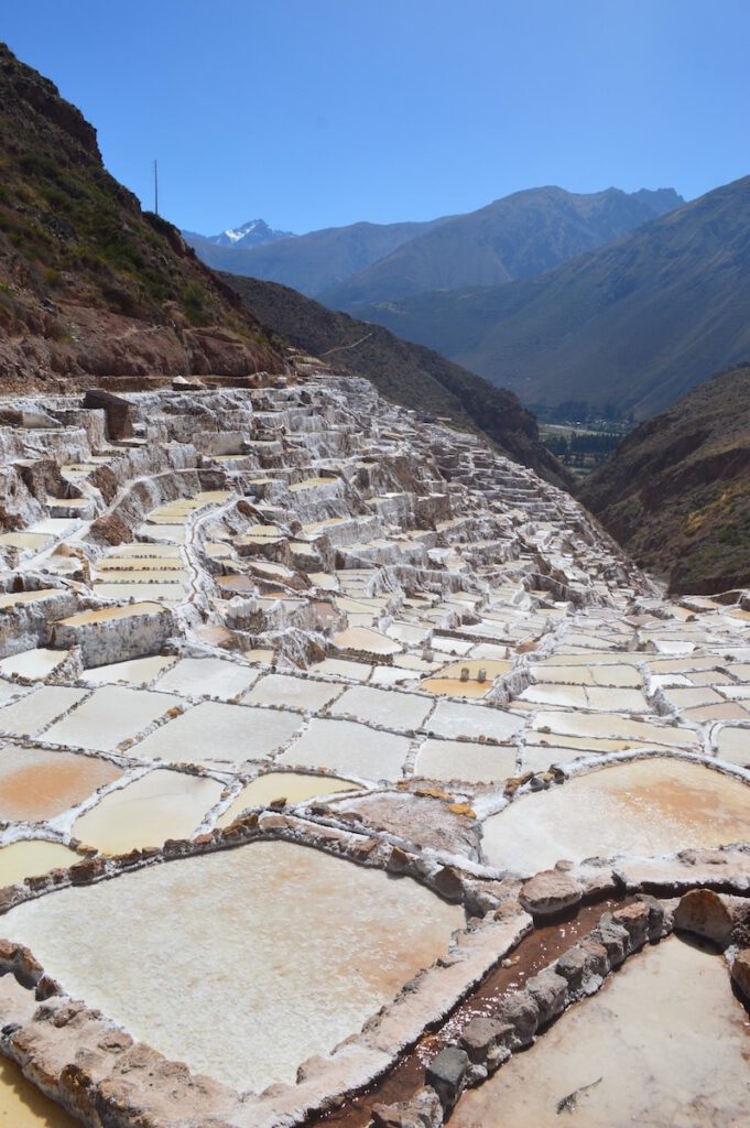 Color photo of checkered salt field in front on high mountains