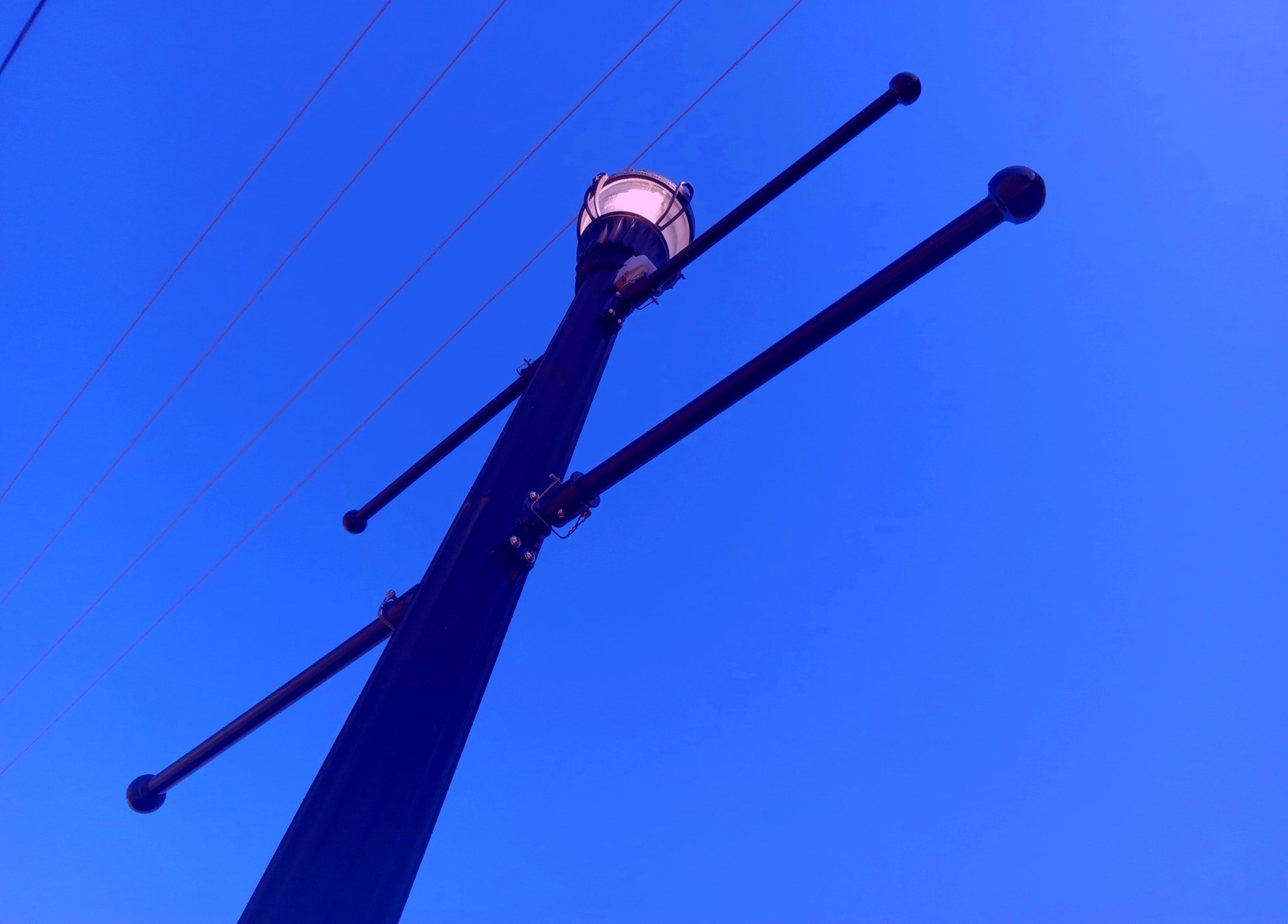 color photo of a lamppost and wires against a dusky blue sky